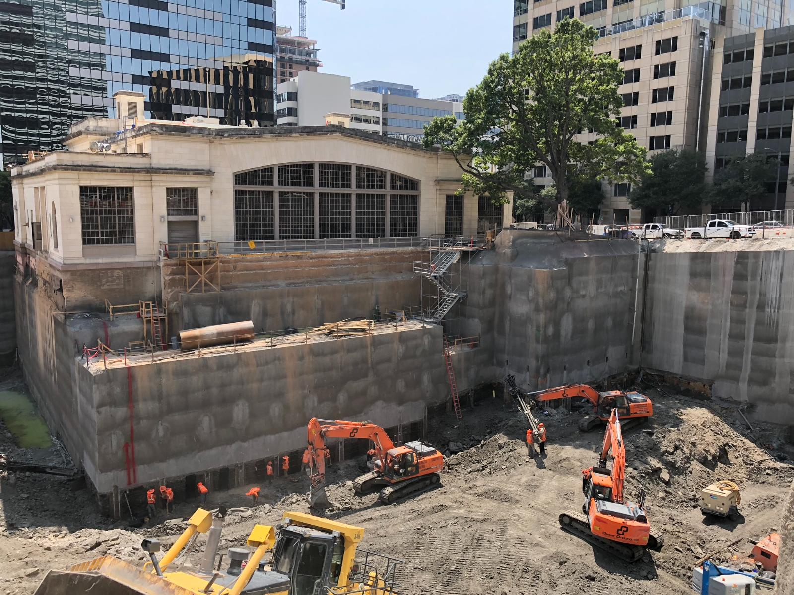 Specialized excavators and field equipment from Oscar Orduno, Inc. performing complex shotcrete and earth retention adjacent to an urban structure for Indeed Tower in Austin, Texas.