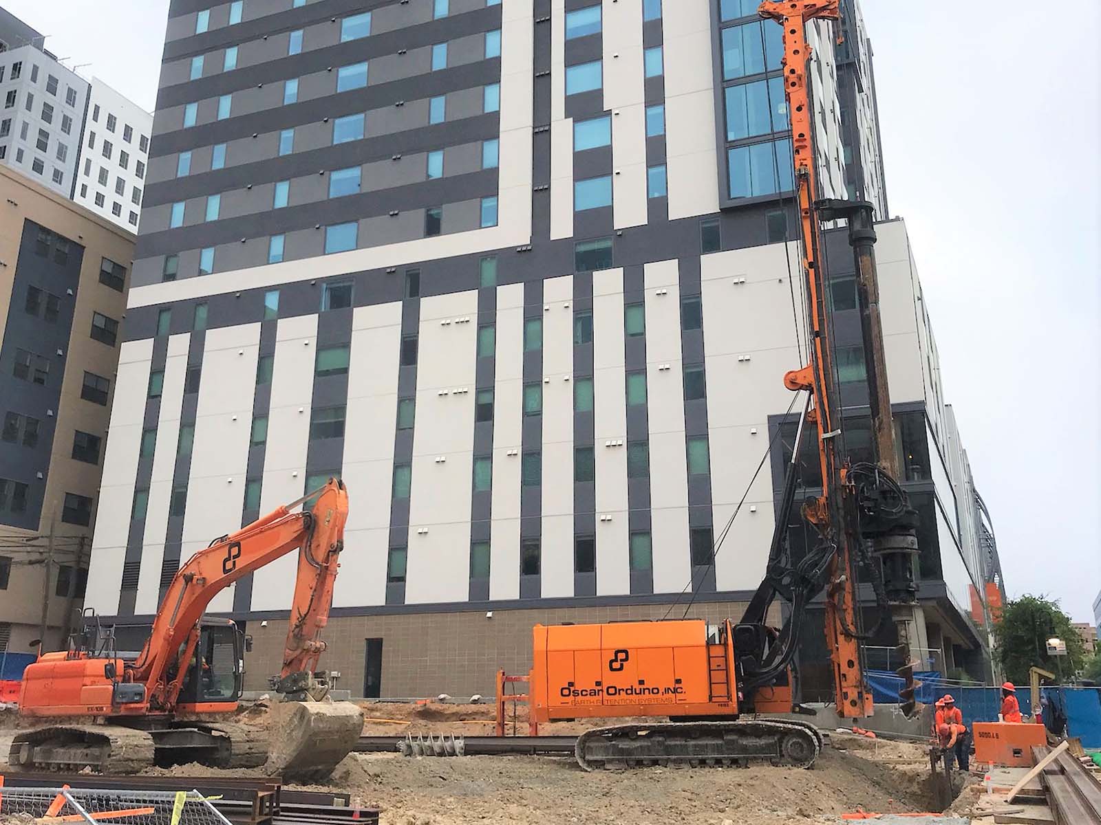 Oscar Orduno, Inc. utilizing specialized drilling rigs and excavators for soldier pile shoring in a high-density urban environment.