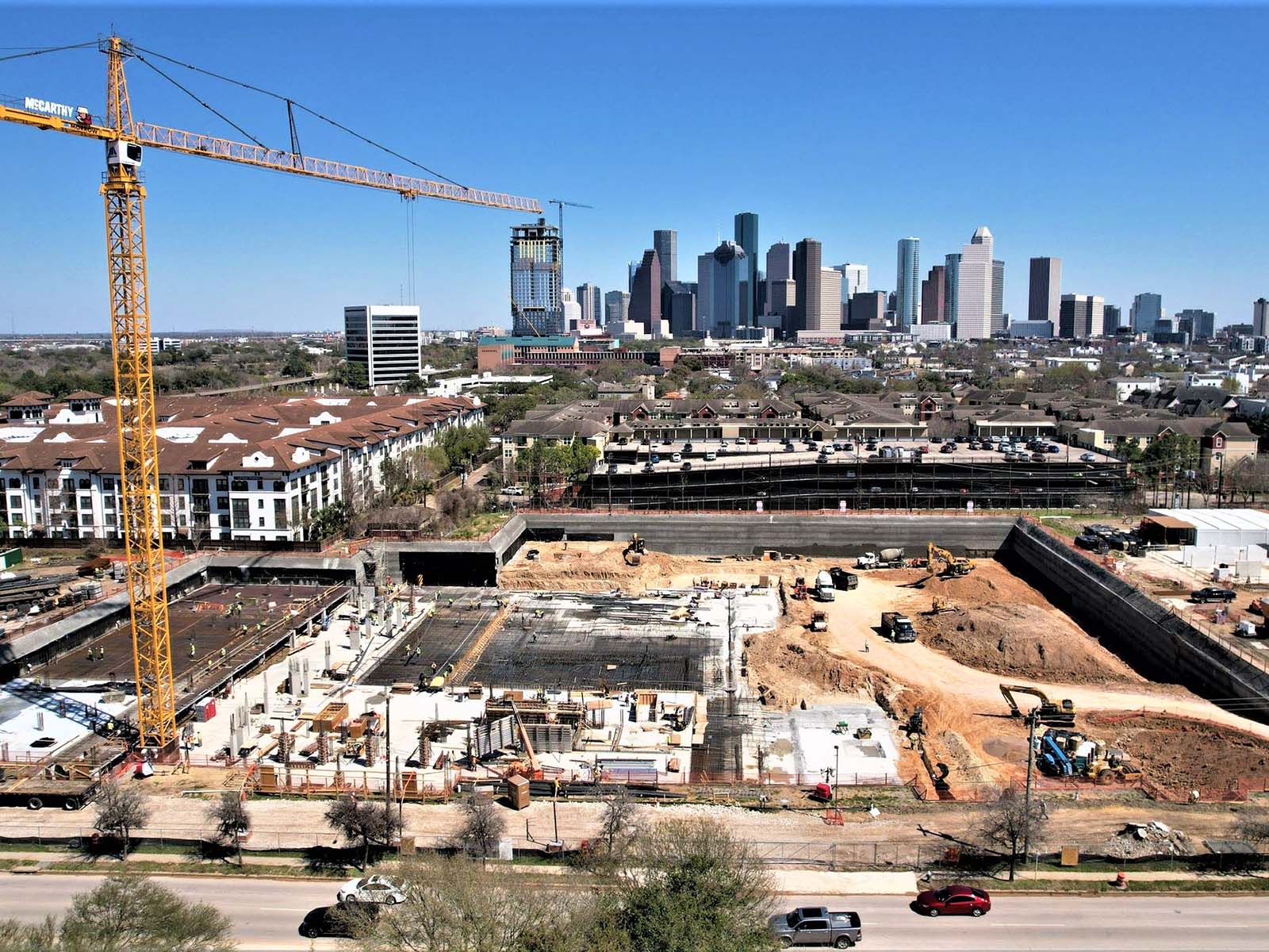 Aerial view of a major urban excavation featuring a foundation rebar grid and shoring walls by Oscar Orduno, Inc. for The Ismaili Center in Houston TX