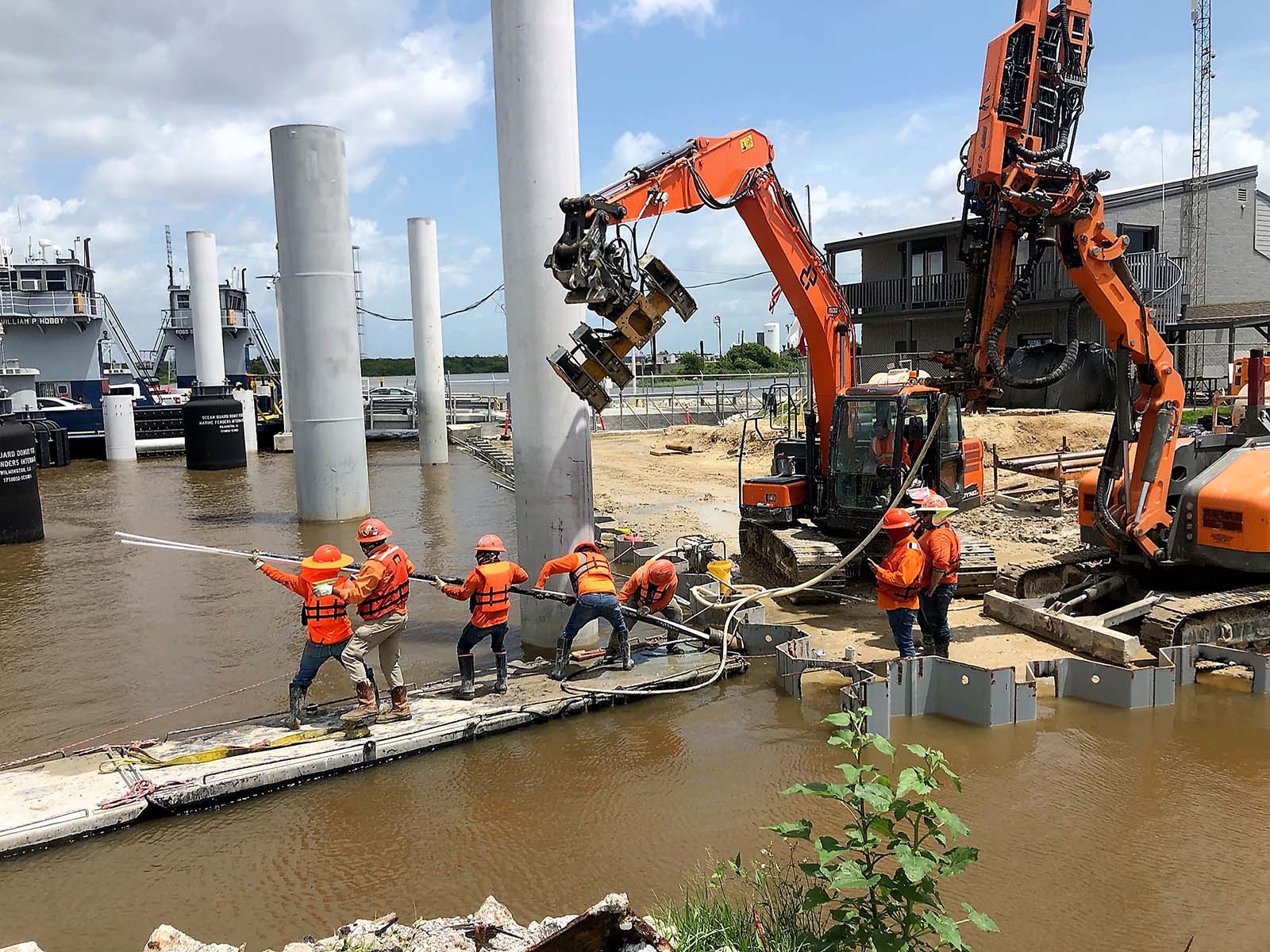 Field crew on a floating barge manually guiding reinforcement rods for Tieback Anchor installation at the Lynchburg Ferry Post in Houston, TX.