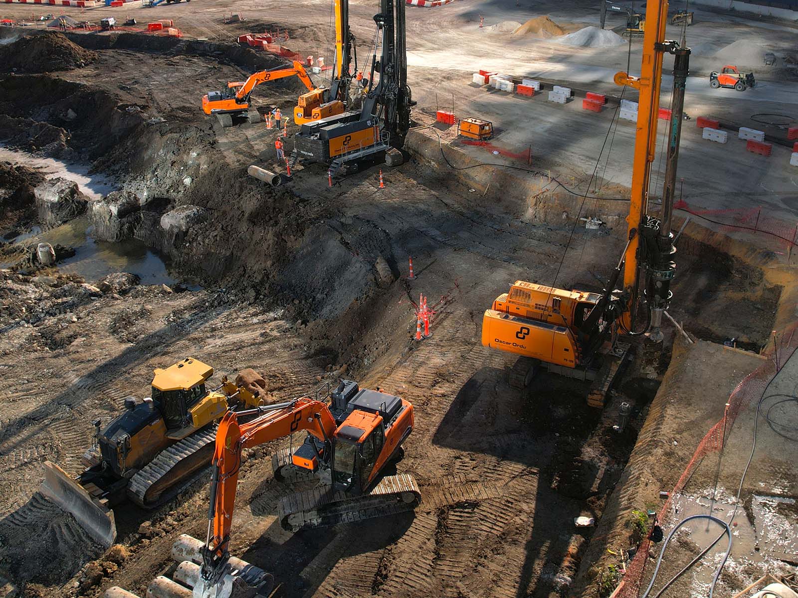 Aerial view of Oscar Orduno, Inc. utilizing specialized drilling rigs and crawler excavators for deep foundation and earth retention work in an urban setting.